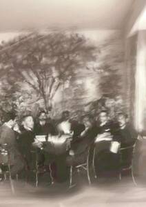 Historische Schwarz-Weiß-Aufnahme einer Personengruppe an Tischen in einem Lokal