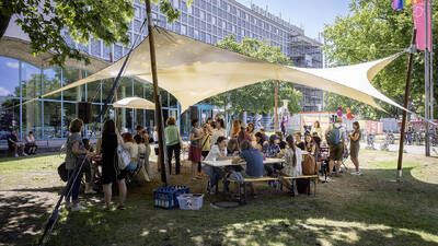 viele Personen sitzen um Tisch herum, draußen