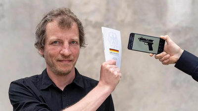 Foto einer Person, die das Grundgesetzbuch und Handy in der Hand hält